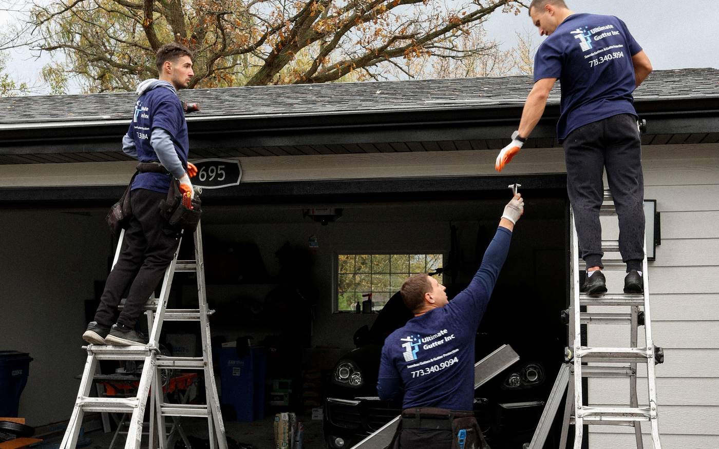 Team on ladders installing gutters