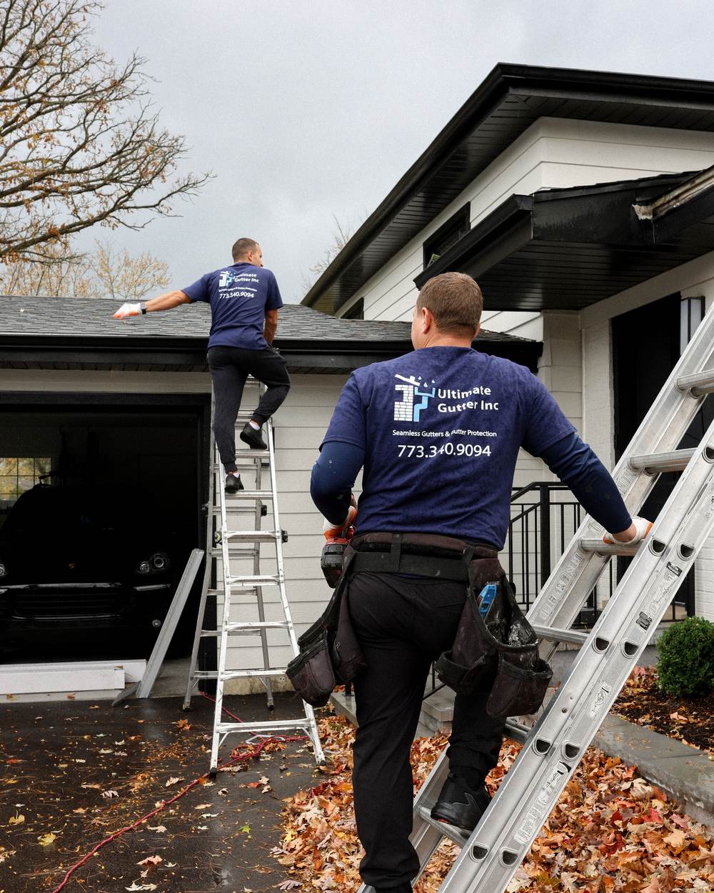 Ultimate Gutter crew installing seamless gutters from ladders at a garage gable